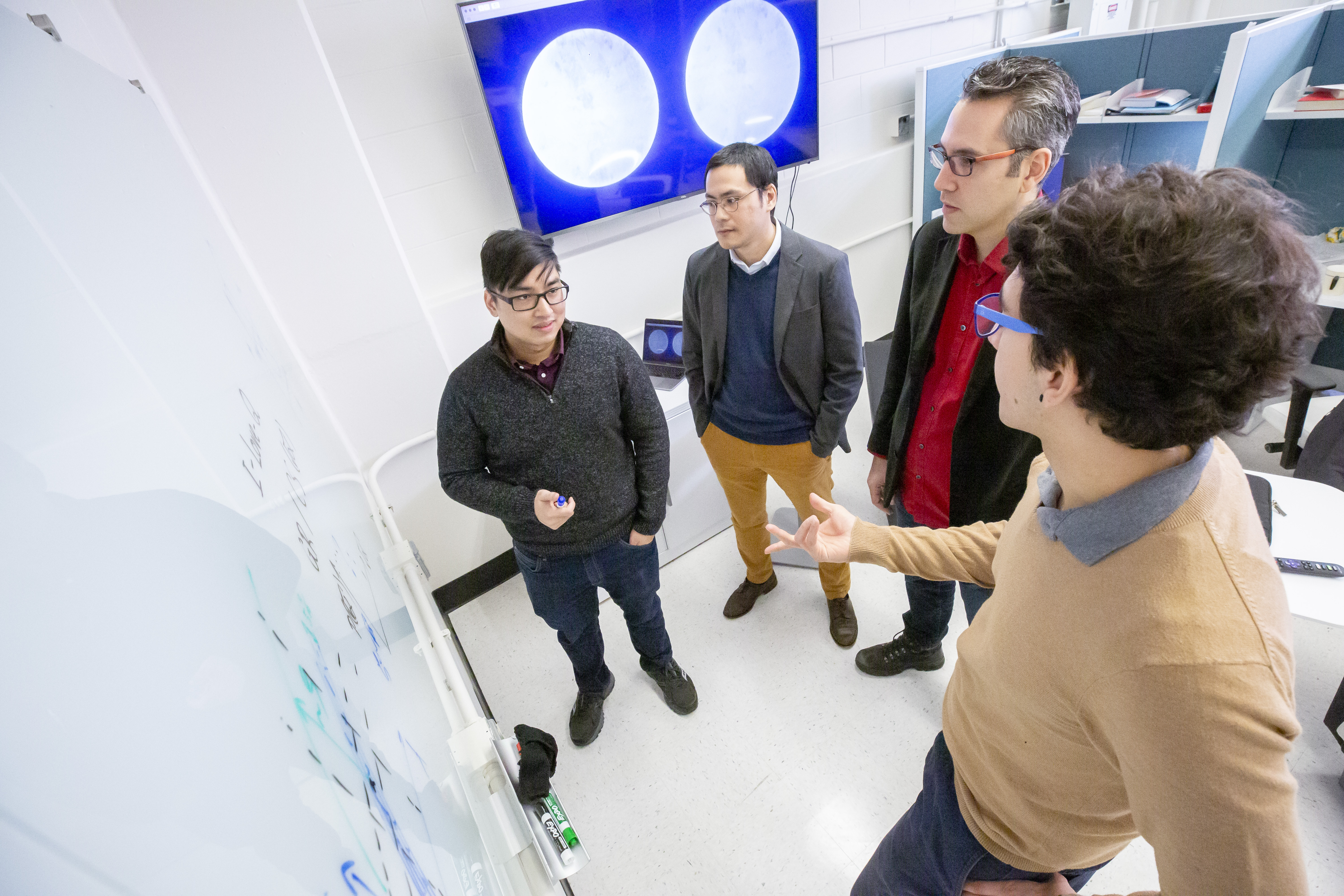 The authors of the paper are working together at a whiteboard.