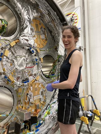 Elle Shaw tightens screws that mount the telescope bases to the cryostat
