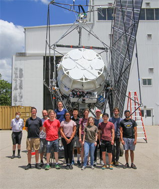 SPIDER team members stand in front of the fully assembled payload. Right before flight the payload will look much different. Before flight, all the external spars will be wrapped in aluminized mylar sheeting, and anything exposed to the sun will be made reflective or be painted white.